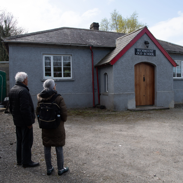 Photo of the back of two Indian people facing a school building